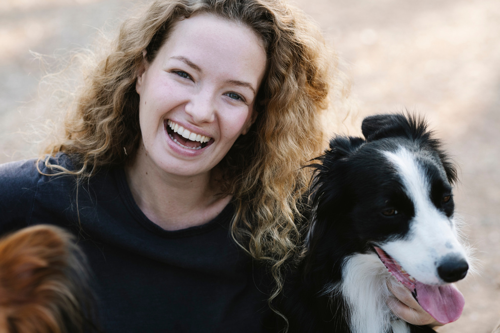 Young woman hugging dogs and laughing